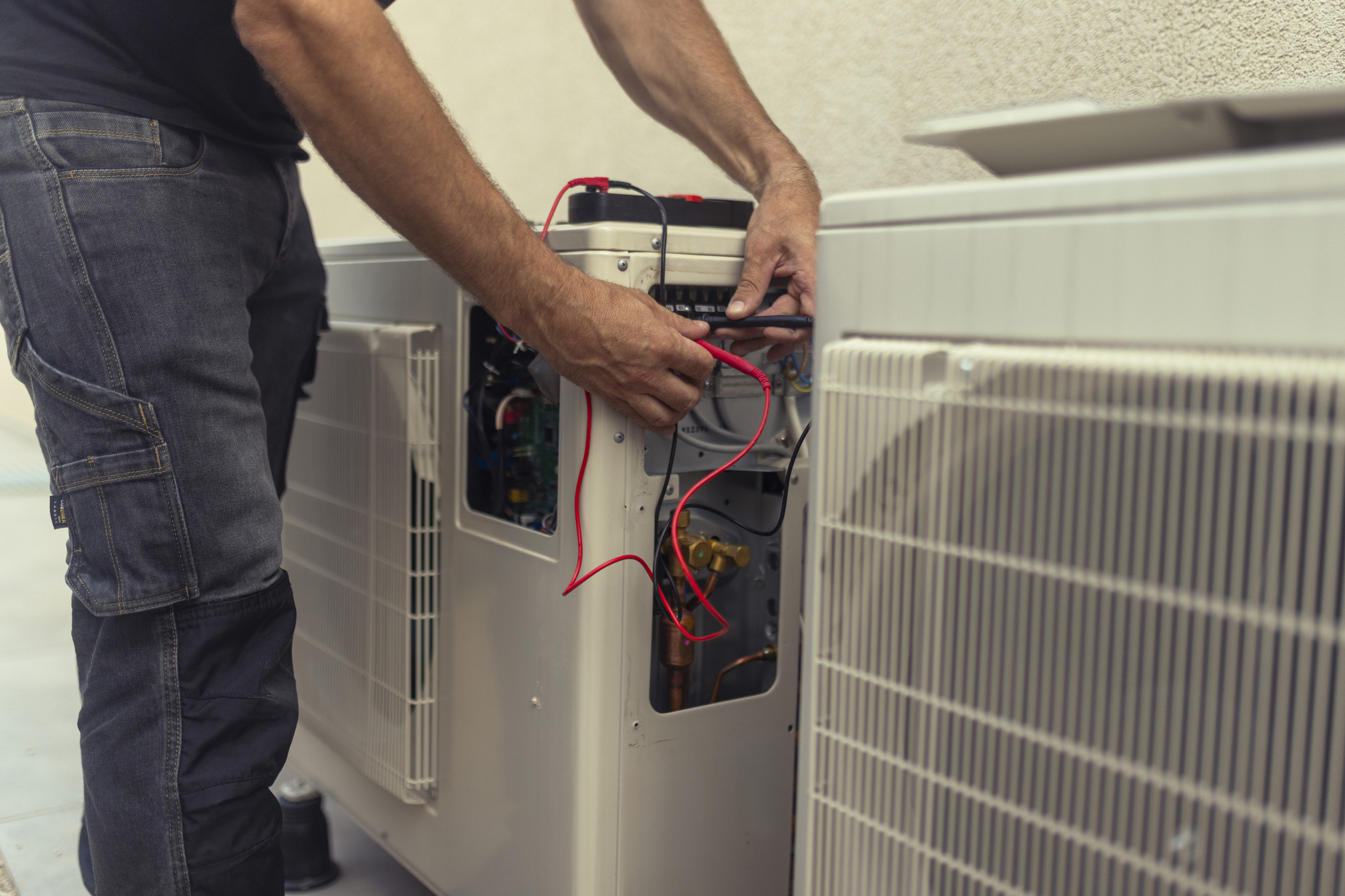 Close-up on the hands of the electrician installing the heat pump, connecting the wires